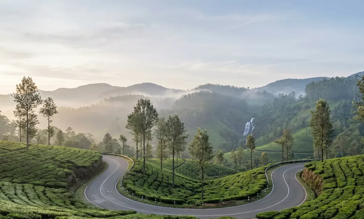 Scenic Tea Garden Drive in Munnar, Kerala Winding mountain road through lush tea plantations with misty hills and a waterfall in Munnar, Kerala